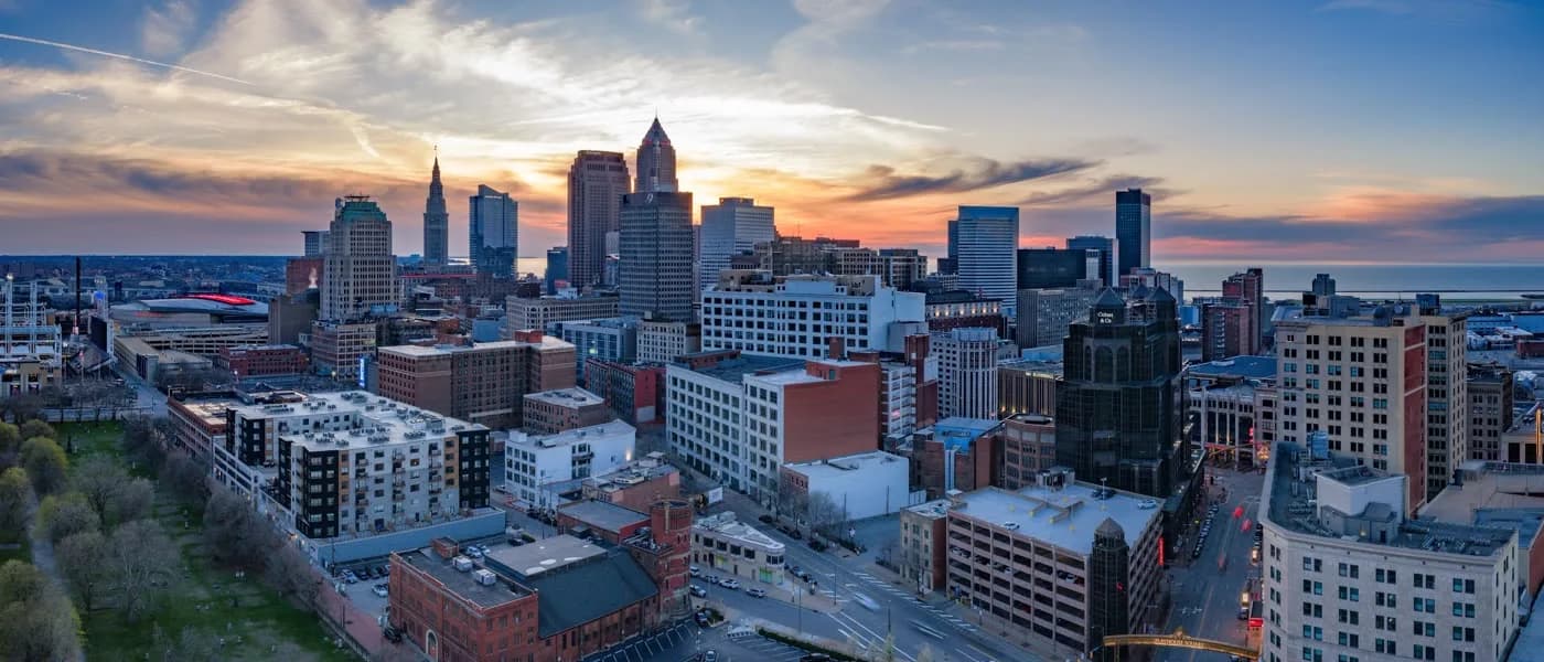 Golden-hour aerial view of the Cleveland skyline against a glowing sky.