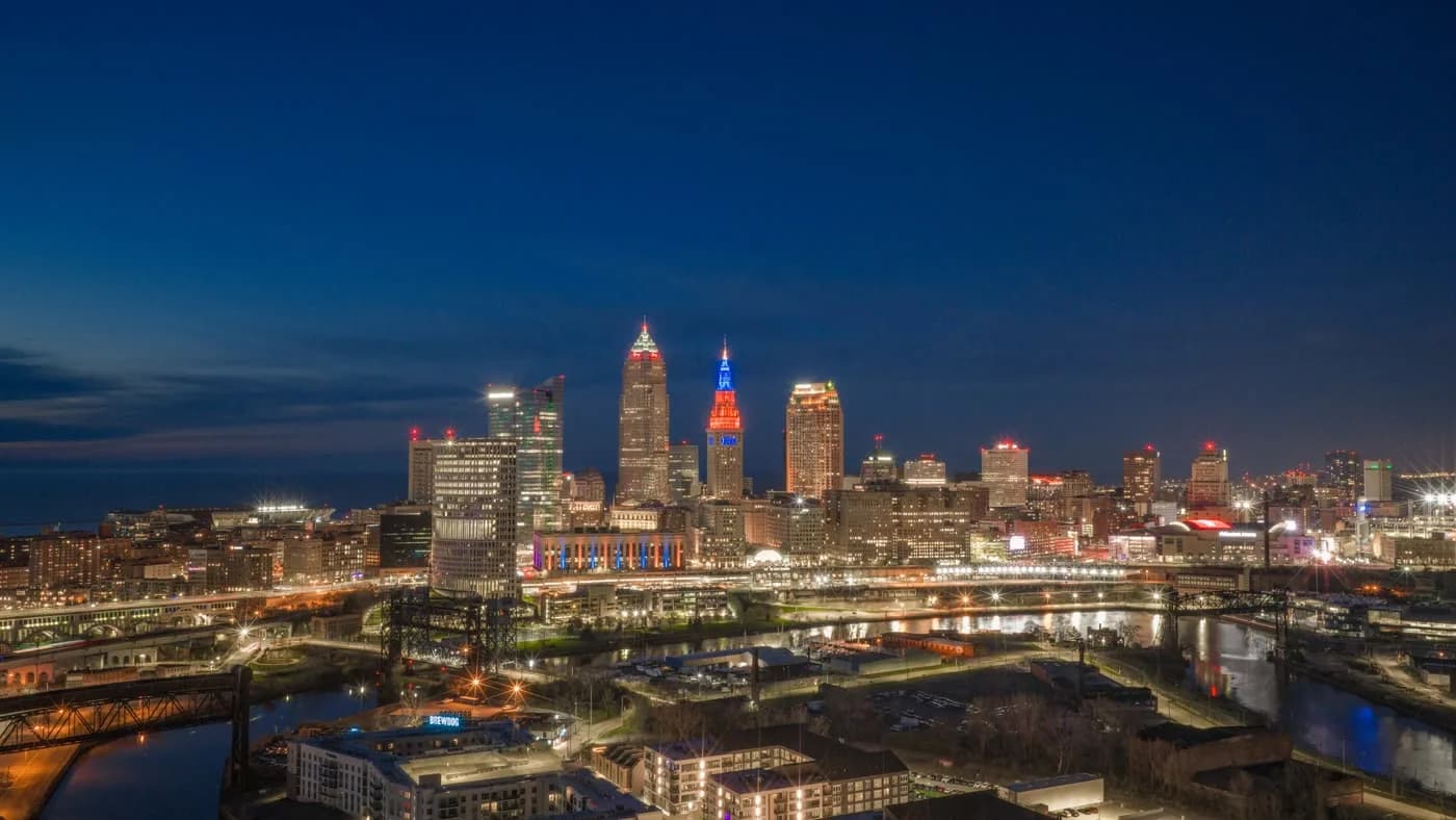 Downtown Cleveland lit up at night, with Terminal Tower in patriotic colors, seen from the air.